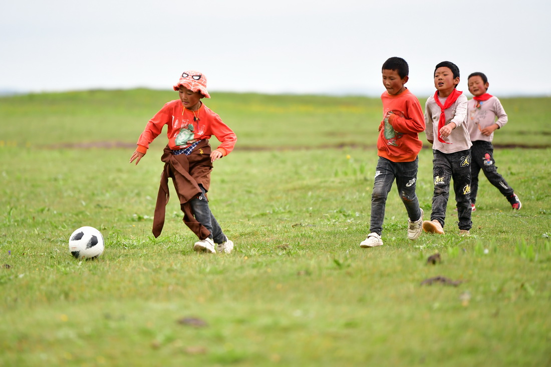 7月14日，河曲馬場小學的孩子在草原上踢足球。