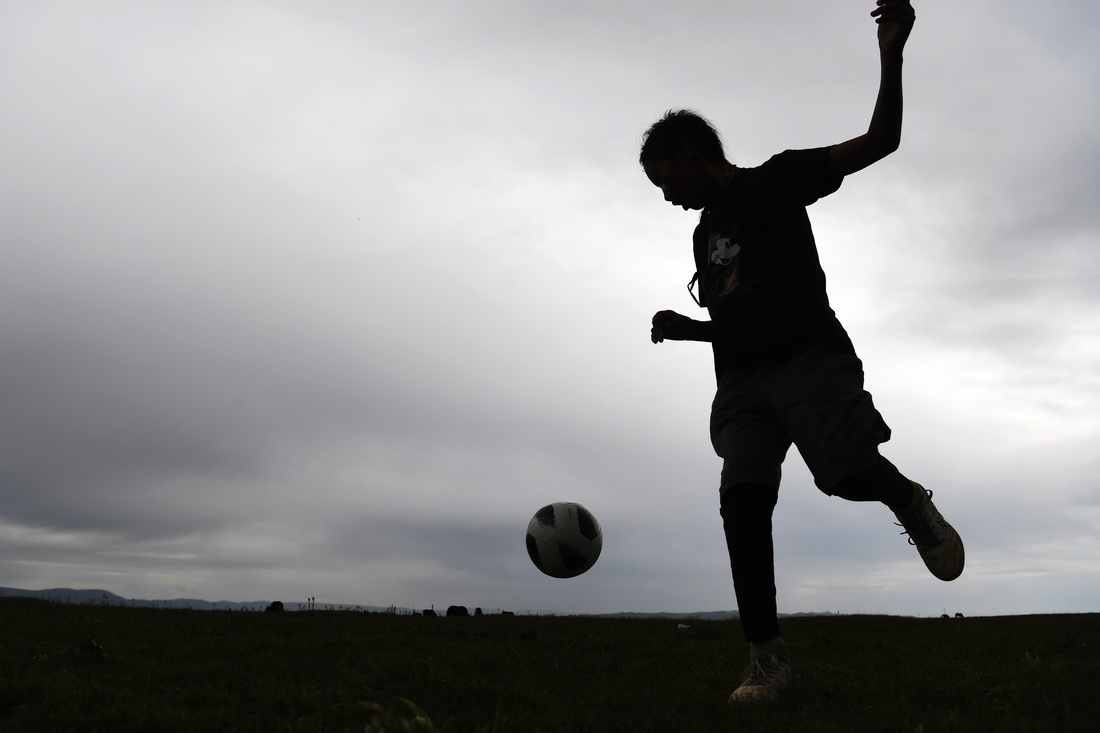 7月14日，河曲馬場小學學生丹增喇巴在草原上踢足球。