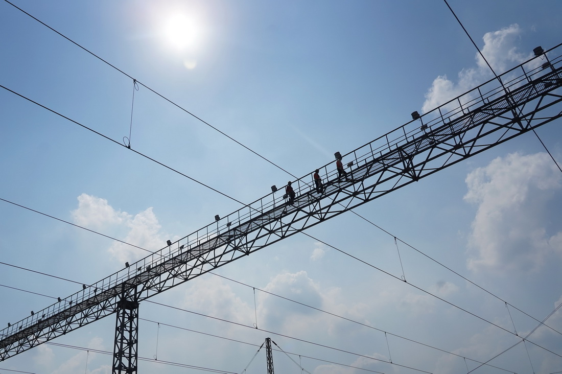 7月14日，電力工人們在南昌西動車所的燈橋上作業。