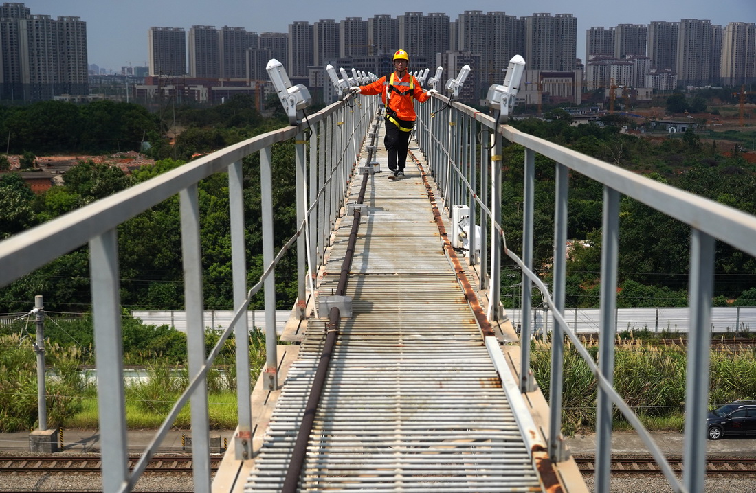 7月14日，電力工人在南昌西動車所的燈橋上巡檢。
