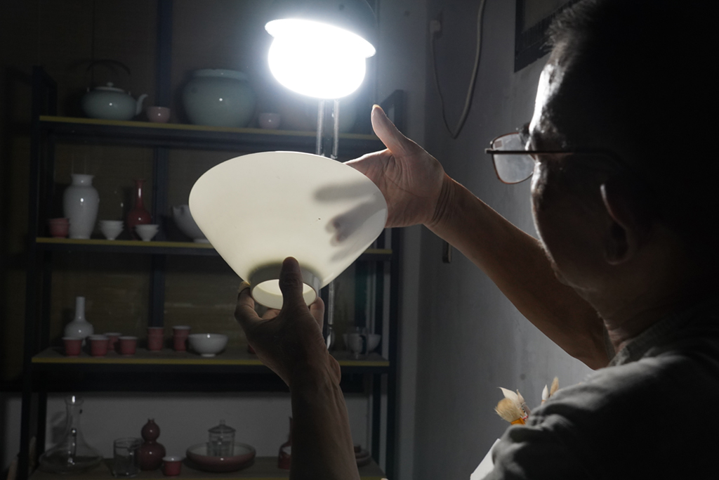 熊國安在檢驗一隻薄胎碗的厚度（7月14日攝）。新華社記者 周密 攝