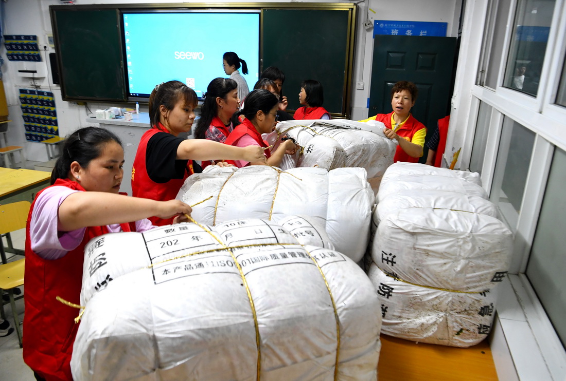 7月21日，在鄭州市電子信息工程學校集中安置點，志願者在整理被褥。