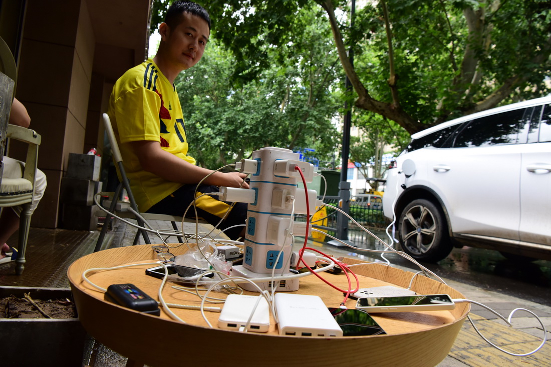 7月22日，一位鄭州市民用私家電動車作為電源為群眾手機、充電寶等臨時充電。