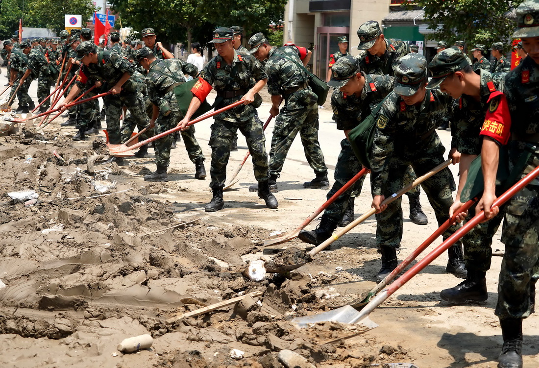 7月25日，救援人員在鄭州市中牟縣進行路面清淤作業。新華社記者 李安 攝