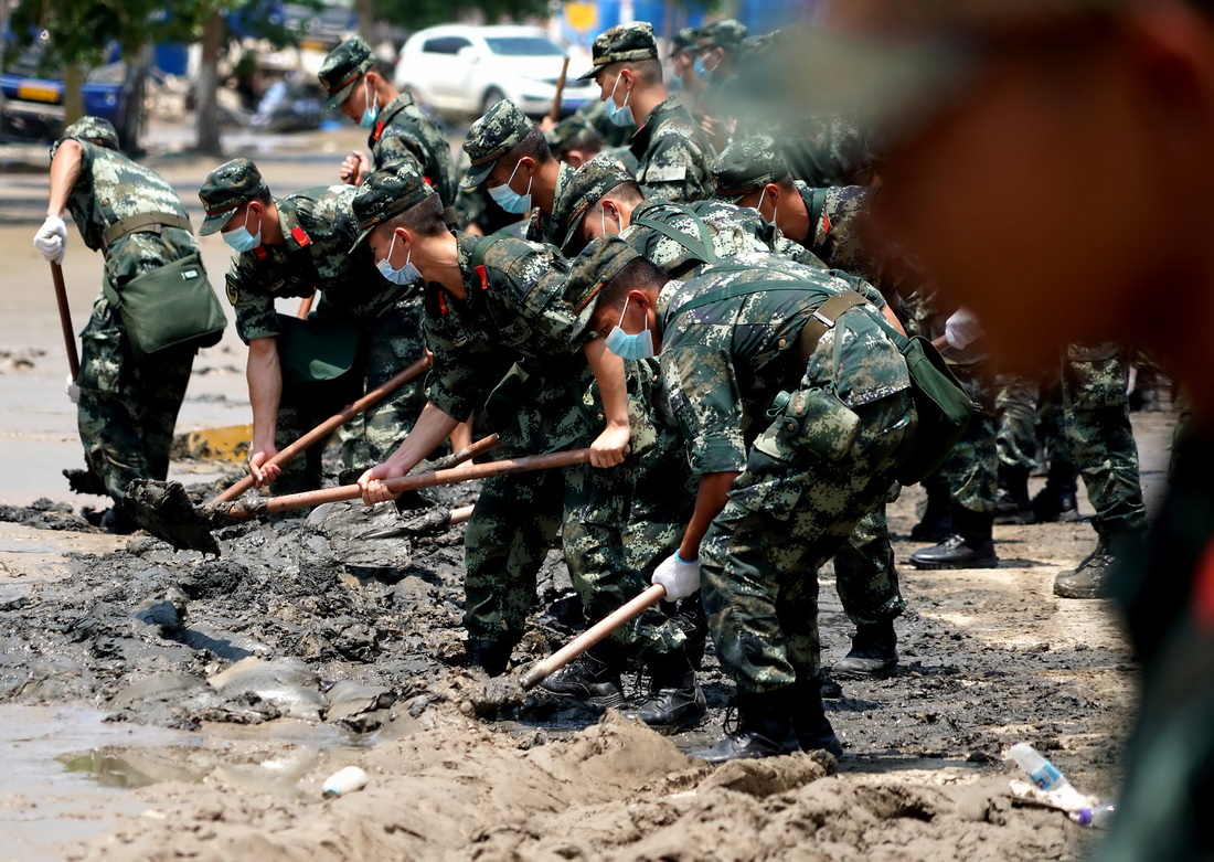 7月25日，救援人員在鄭州市中牟縣進行路面清淤作業。新華社記者 李安 攝
