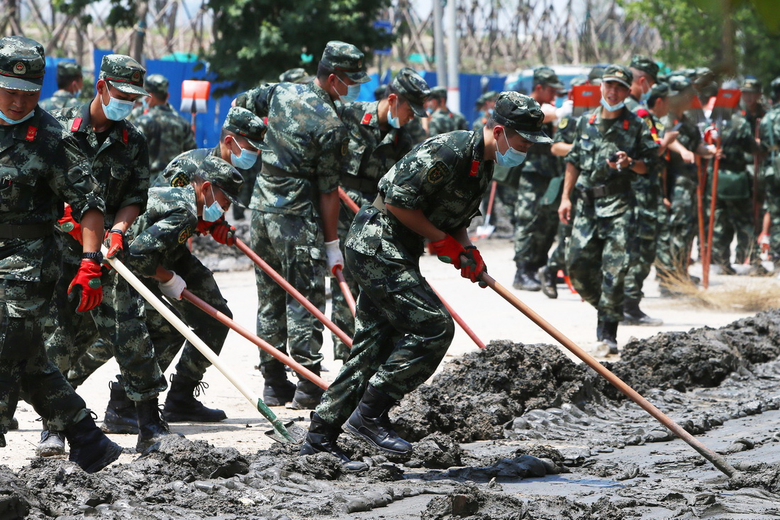 7月25日，救援人員在鄭州市中牟縣進行路面清淤作業。新華社記者 許雅楠 攝