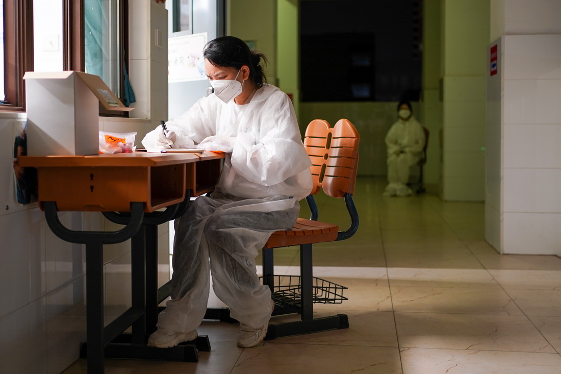 7月24日，在南京市江寧區龍西社區核酸檢測點，社區志願者殷慧（左）在整理社區居民登記信息。新華社記者 李博 攝