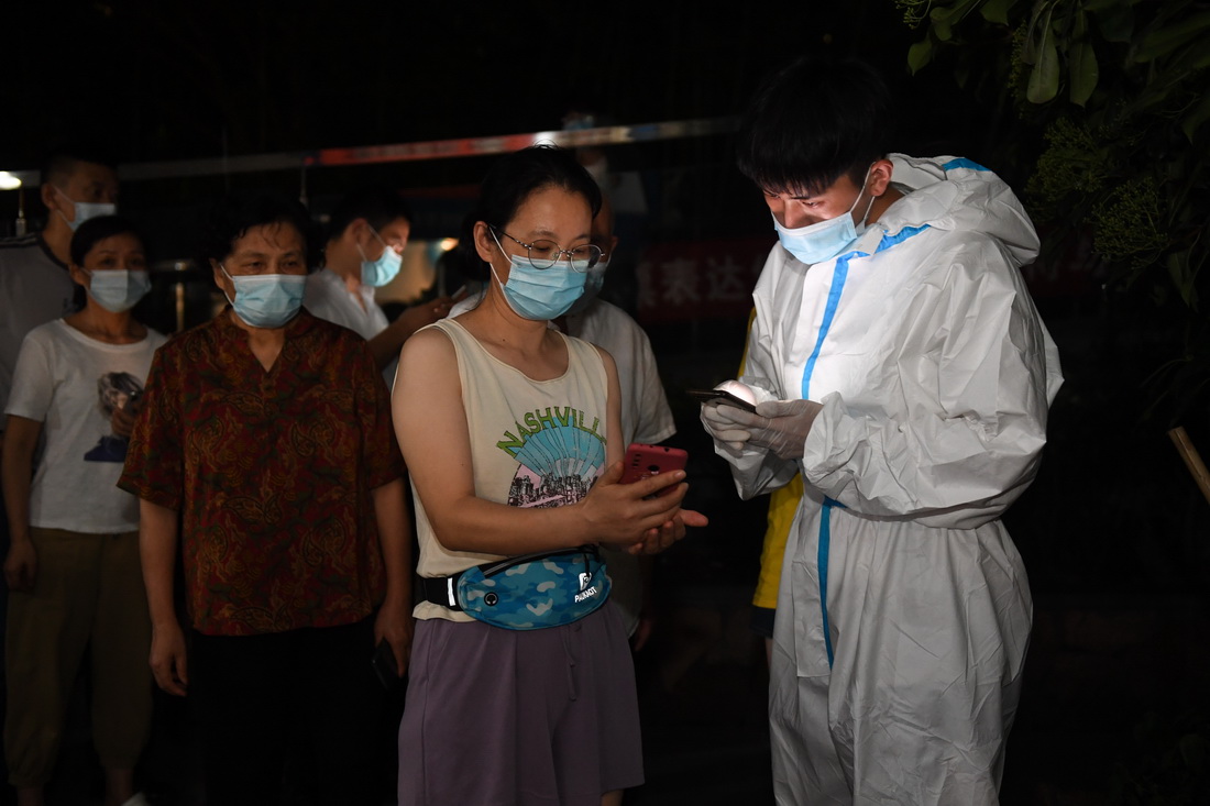 7月24日，在南京市江寧區秣陵街道高爾夫國際花園小區核酸檢測點，社區網格員劉明輝（前右）在幫助居民登記信息。新華社記者 季春鵬 攝