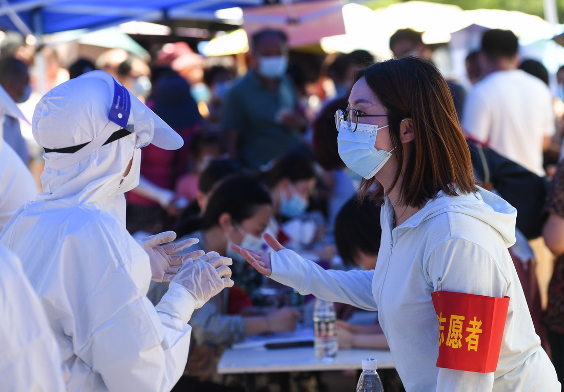 7月21日，在南京市江寧區萬科·金域藍灣小區核酸檢測點，醫生和社區志願者交流。新華社記者 季春鵬 攝