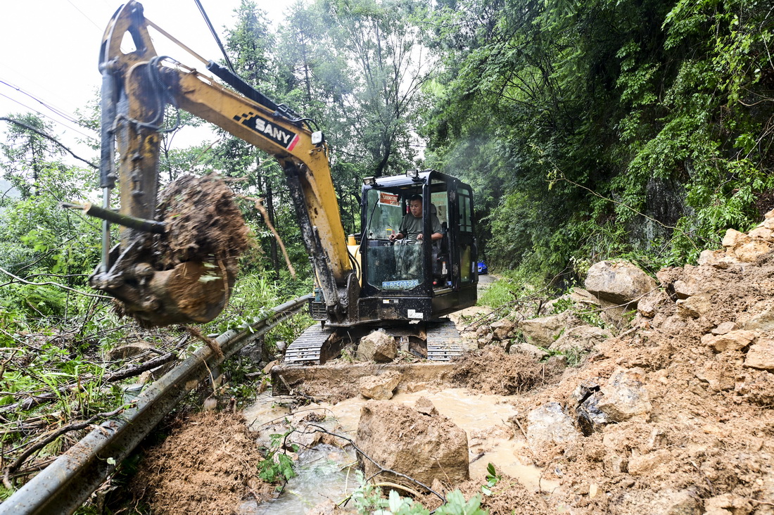 7月26日，在浙江省金華市磐安縣大盤鎮林豐村，救援人員冒雨清理塌方山石樹木。新華社發（胡肖飛 攝）