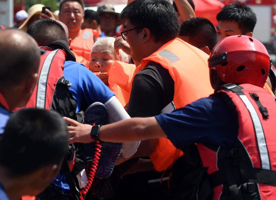 7月27日，在积水严重的卫辉城区，救援人员在转移被困群众。新华社记者 李嘉南 摄