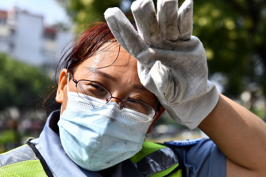 8月4日，济南市城管局城肥清运管理一处女子清疏班赵芸在作业时擦拭汗水。