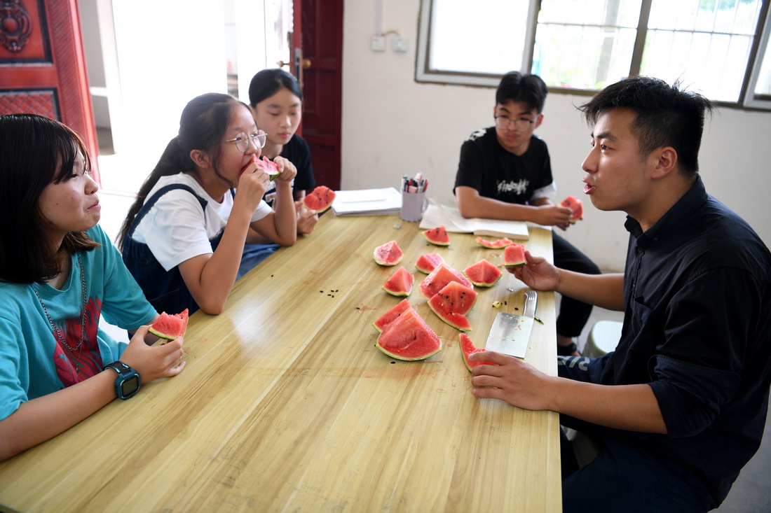 8月3日，课间休息时间，周伟杰和孩子们一起吃西瓜消暑。新华社记者 黄博涵 摄
