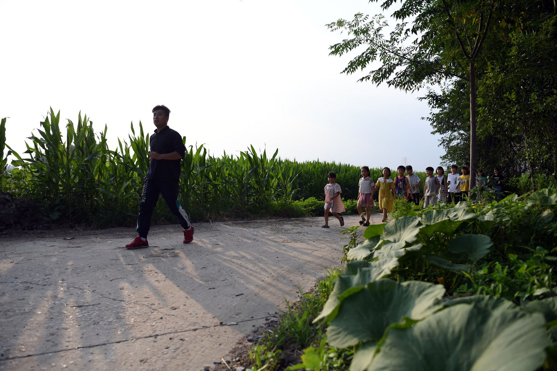 8月3日，周伟杰带孩子们在乡村道路上步行。新华社记者 黄博涵 摄