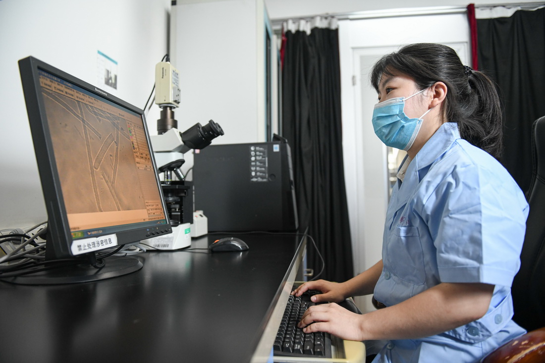 海口海关技术中心工作人员陈淑娟在实验室通过电子显微镜观察离岛免税服饰纤维成分（7月13日摄）。