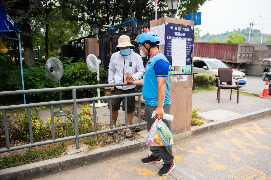 8月9日，在张家界永定区蓝色港湾小区，外卖员燕赢召在小区门口出示健康码。