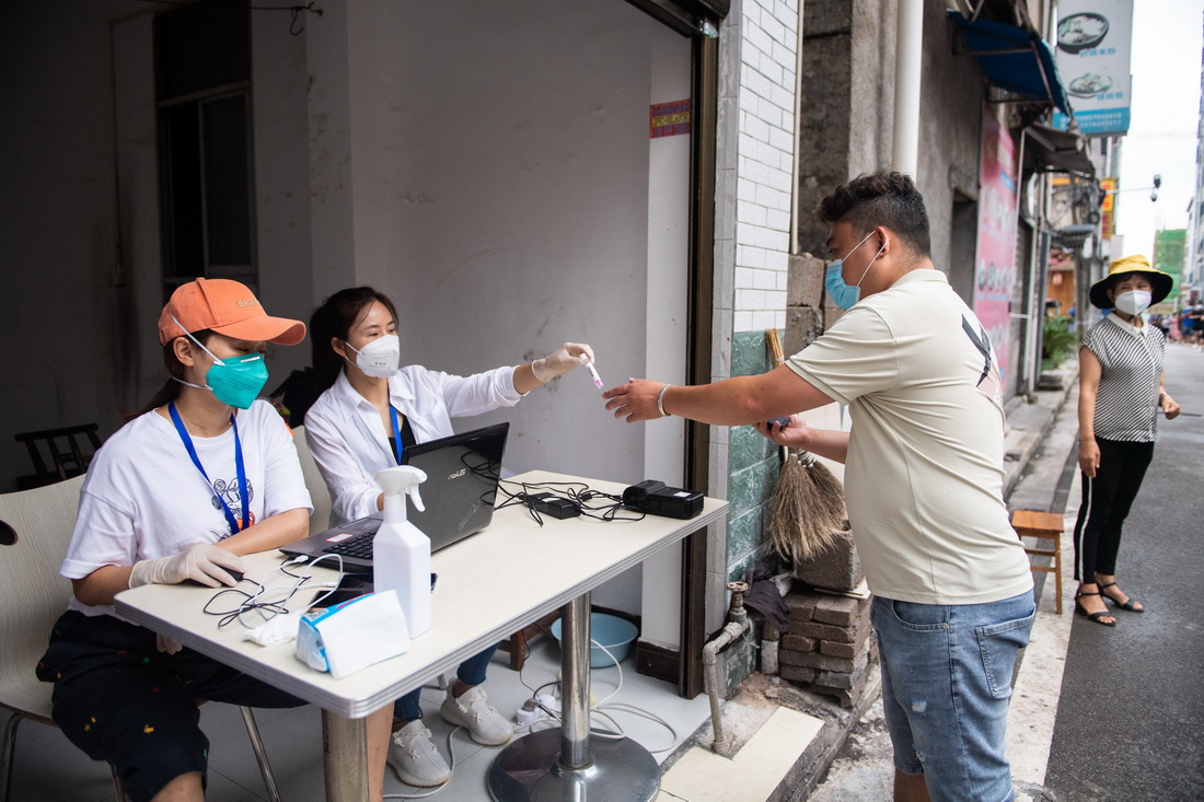 8月10日，在張家界市永定區官黎坪街道，居民登記后領取核酸檢測試管。