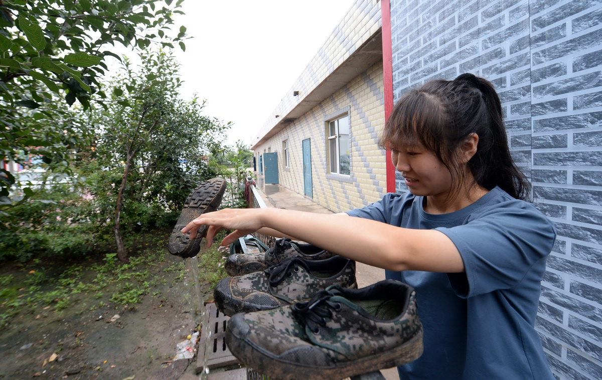 李水英清理在田里沾满泥水的鞋子（8月11日摄）。