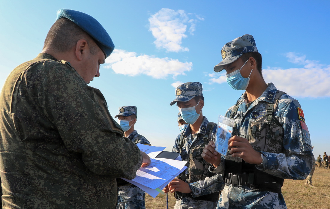 8月23日，在俄羅斯梁贊州日多瓦空降場，參加“空降排”空降兵分隊比賽的中國參賽隊隊員進行賽前身份檢錄。新華社發（方超 攝）