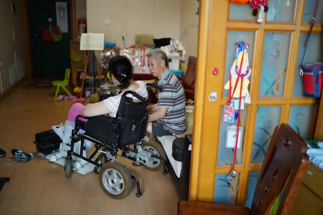 王磊（左）一邊做運動器械練習，一邊與父親王倫甫交談（8月23日攝）。新華社記者 周密 攝