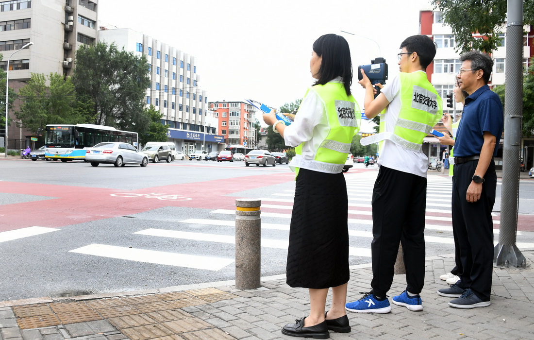 在北京交通大学西门附近的一个十字路口，邵春福（右一）与学生们一起数车（8月28日摄）。