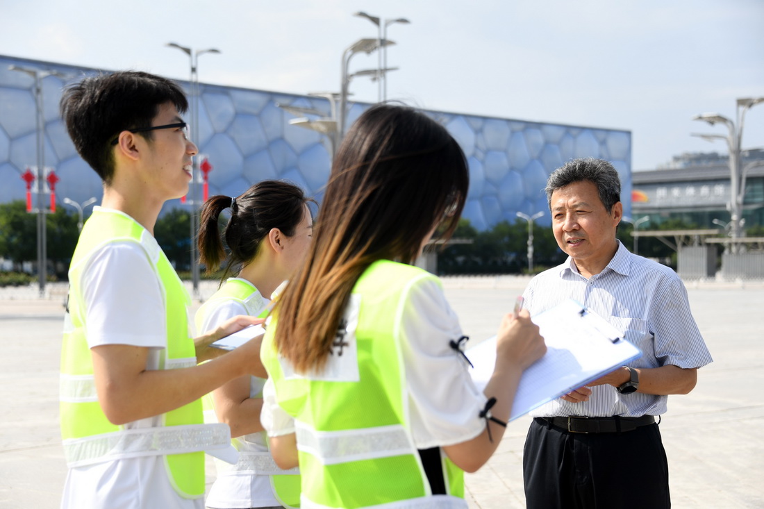 在北京国家体育场附近，邵春福（右一）为学生们讲解交通调查在大型场馆周边交通疏散中的应用（8月20日摄）。