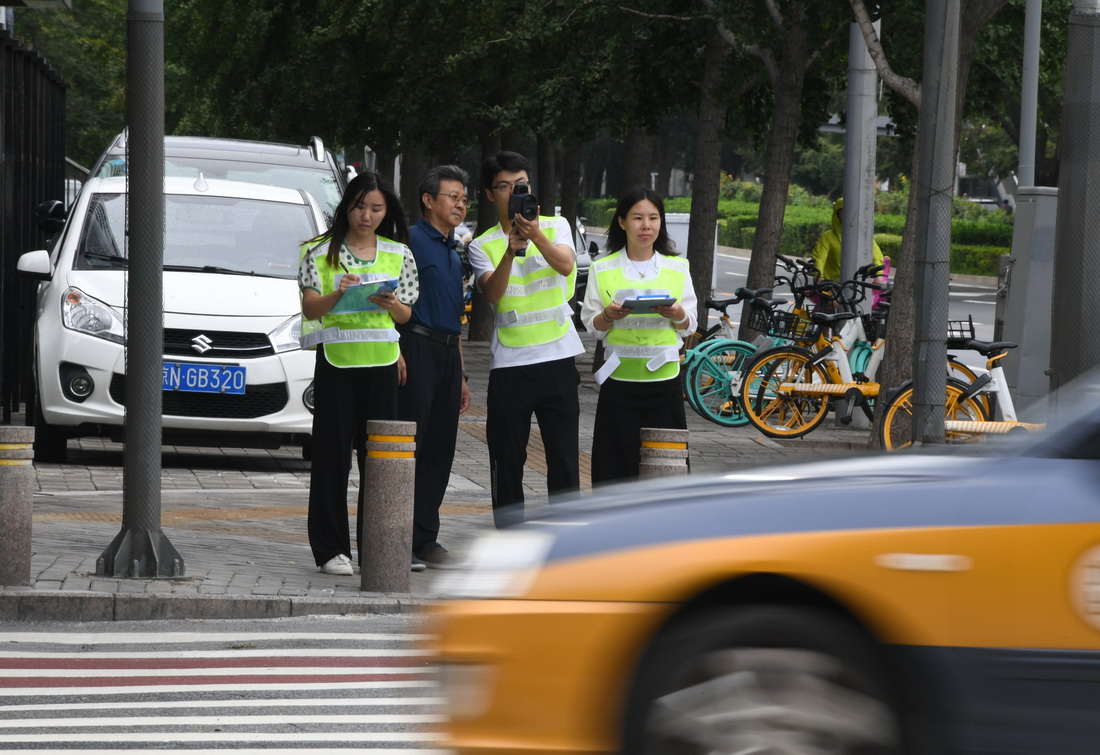 在北京交通大学西门附近的一个十字路口，邵春福（左二）与学生们一起数车（8月28日摄）。