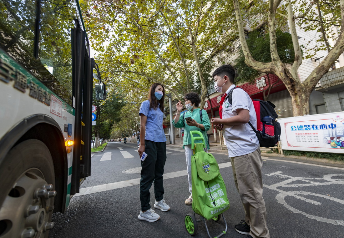 9月6日，在公交線路中一處學生上車點，一名家長向武艷夢（左）咨詢乘車事宜。新華社記者 陳欣波 攝