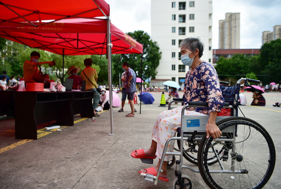 9月12日，居民坐着轮椅在莆田市仙游县鲤城街道坝垅社区操场等待做核酸检测。