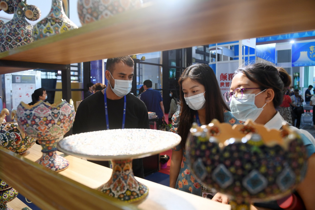 9月12日，在广西南宁国际会展中心，来自伊朗的胡文宇（左一）在向顾客介绍参展商品。新华社记者 陆波岸 摄