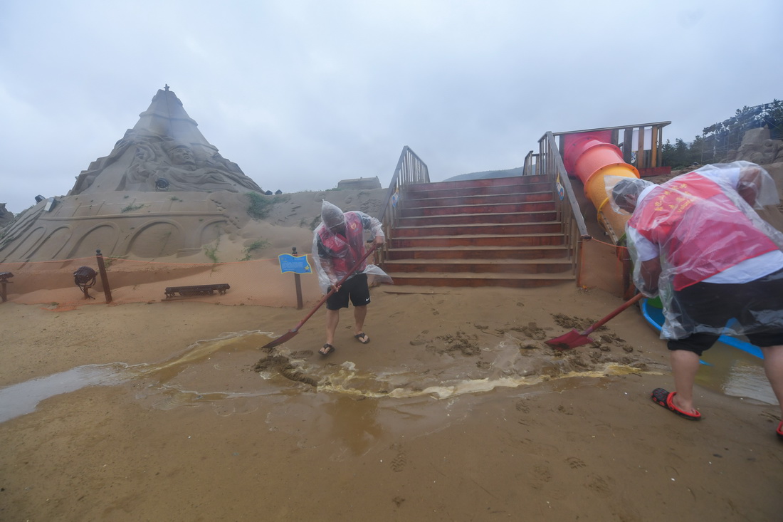 9月14日，黨員志願者在舟山朱家尖南沙景區的沙雕區挖溝排水。