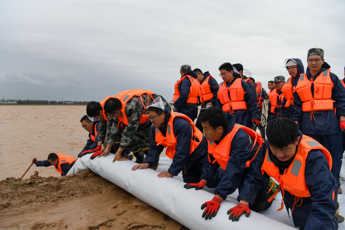 10月4日，在山东省邹平市码头镇段家村黄河生产堤上，抢险人员铺设土工膜。新华社发（李晓伟 摄）