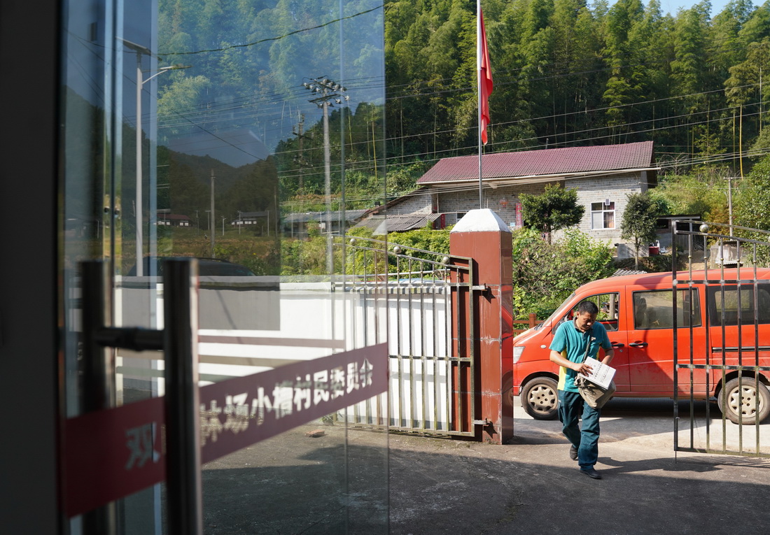 9月28日，雙峰郵政所的郵遞員吳文清為村民送報紙。