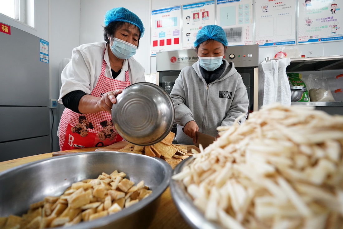 10月11日，在山西省稷山县清河镇吴璧小学安置点，食堂工作人员在为孩子们准备午餐。