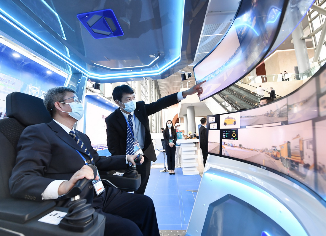 10月14日，在北京國家會議中心，參觀者在工作人員的介紹下體驗模擬操控道路施工設備的“智慧駕艙”。