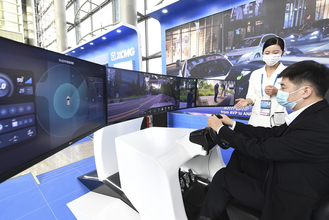 10月14日，在北京国家会议中心，参观者在工作人员介绍下体验操控5G云代驾座舱。