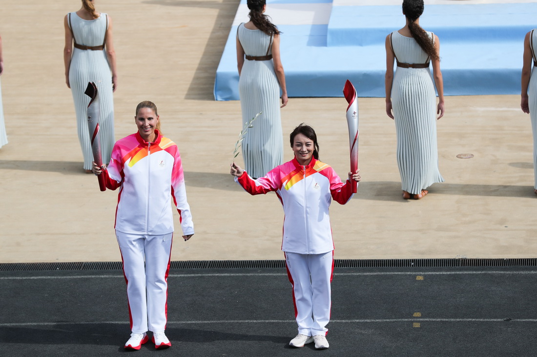 10月19日，場內第一棒火炬手、希臘前水球運動員埃薇·莫賴蒂祖與中國前女子自由式滑雪空中技巧運動員李妮娜（前右）進行火炬傳遞。