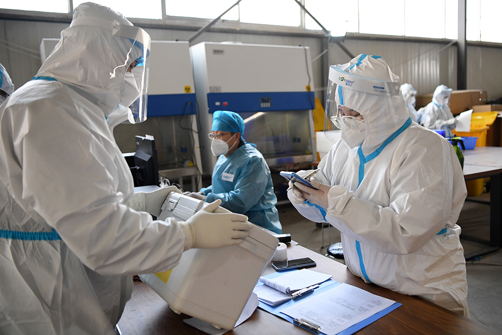 10月24日，在“獵鷹號”硬氣膜實驗室外，工作人員在預處理區交接核酸樣本。