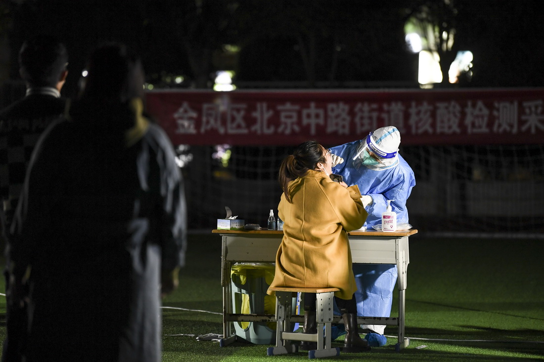 10月23日，在寧夏銀川市金鳳區北京中路街道採樣點，寧醫大總院輪轉醫生馬生萍（右一）為居民進行核酸採樣。