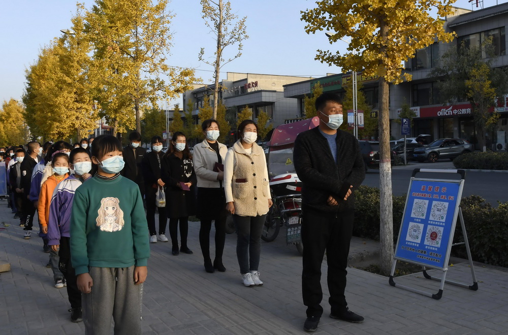 10月29日，在甘肅省永靖縣，學生在家長的陪護下等候接種疫苗。