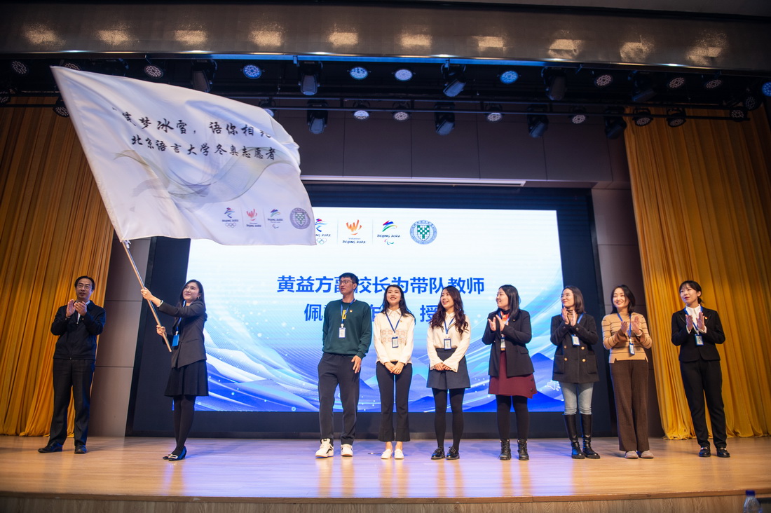 10月31日，北京語言大學冬奧會志願者帶隊教師鄒濼銥（左二）在開班儀式上揮舞隊旗。