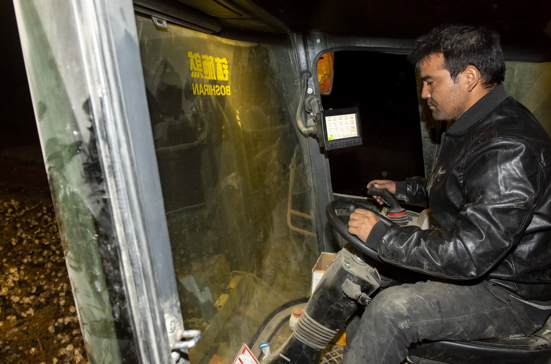 10月25日晚，在新疆沙雅縣托依堡勒迪鎮的一處棉田裡，艾買爾·艾則孜在駕駛採棉機採收棉花（10月25日攝）。為了提高採棉效率，採棉機除了日常保養外，全天不間斷作業，駕駛員們輪流休息。