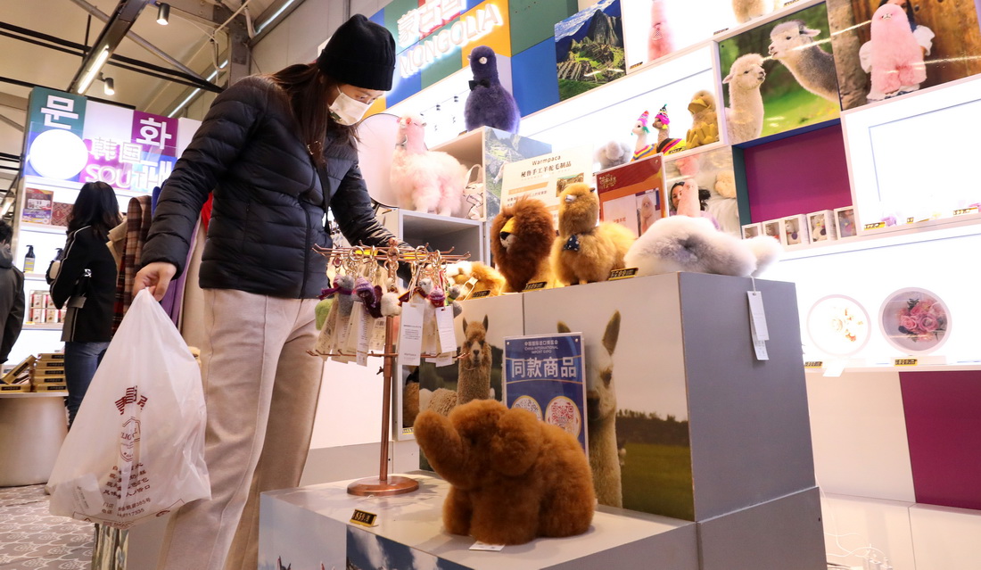 11月8日，顧客在進博集市內撫摸由秘魯羊駝毛制作的玩偶。