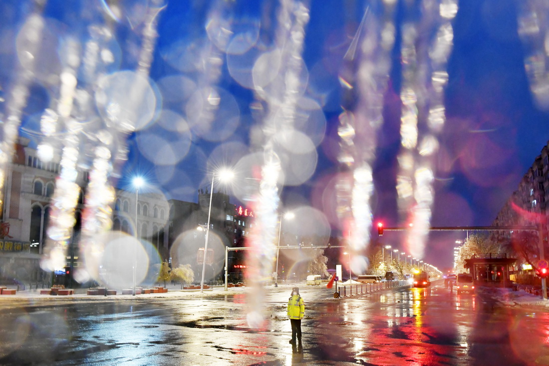 11月8日，在哈尔滨市平房区，一名交通辅警在冻雨中指挥交通。
