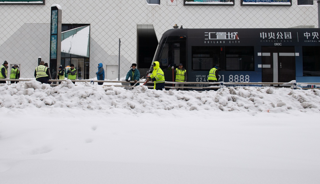 11月9日，在沈阳市浑南区，环卫工人在一辆有轨电车旁清理积雪。新华社记者 蔡湘鑫 摄