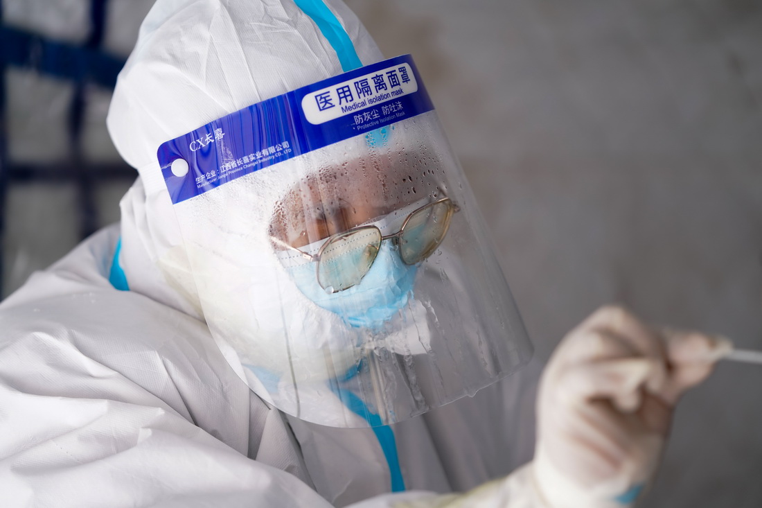 在黑河市愛輝區一核酸採集點，醫務人員在進行核酸採樣（11月9日攝）。