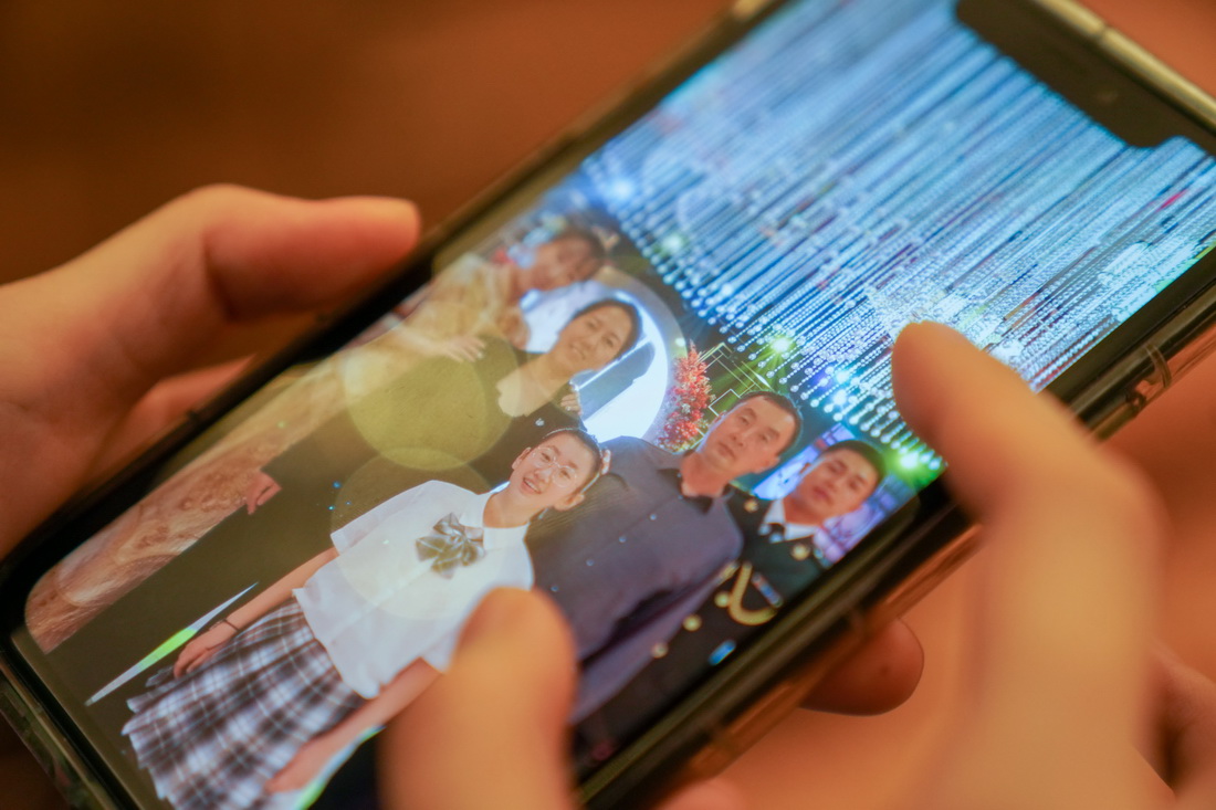 劉冰在“火眼”移動方艙實驗室駐地端詳手機中家人照片（11月14日攝）。