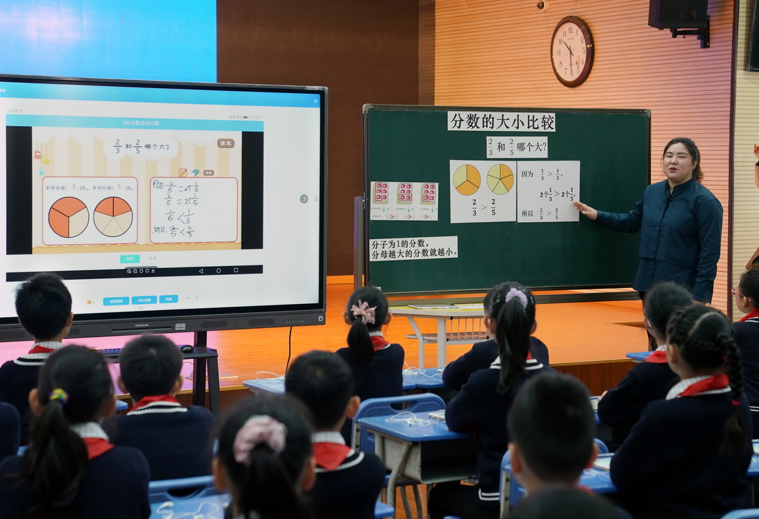 11月18日，在上海市楊浦區平涼路第三小學的“教學助手”展示課上，老師在黑板上進行知識點講解分析，顯示屏上有學生們的人機互動結果和學習效果的統計數據。
