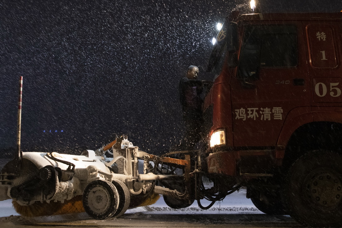11月21日晚，清雪車司機在雞西市雞冠區雞東新路上對車輛進行清理。