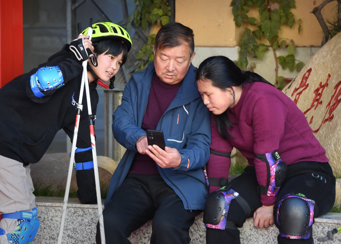 在河南省洛陽市欒川縣特殊教育學校操場內，教練萬清雅（中）讓越野滑雪隊的隊員劉嬌涵（右）、李釔諾看視頻糾正動作（11月18日攝）。新華社記者 李安 攝